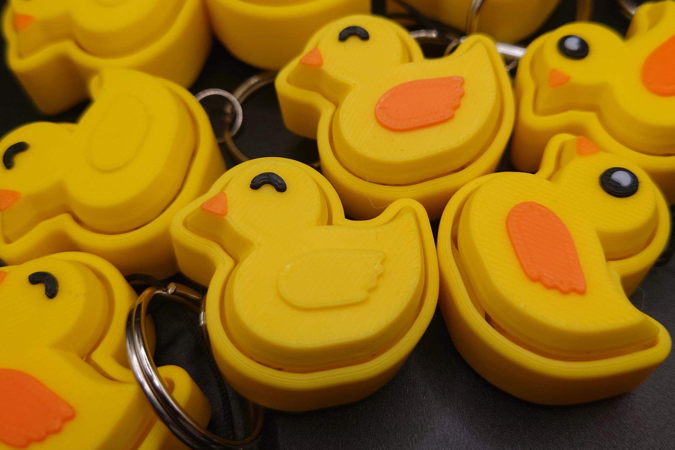 Yellow rubber duck keychains with orange beaks on a black background